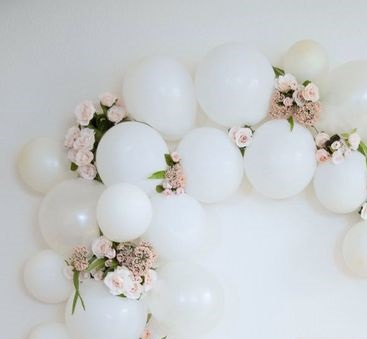 15 white air filled balloon bouquet inserted at intervals with 20 pink flowers